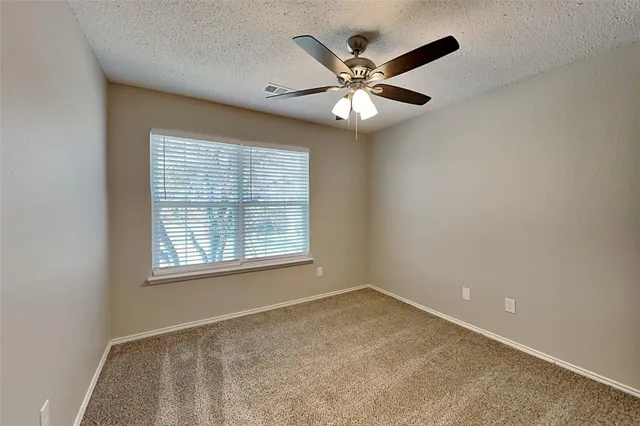 an empty room with a window and a fan