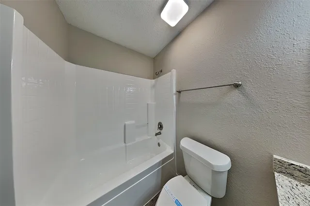 a white toilet sitting next to a bath tub and a shower