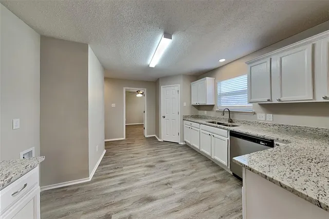 a large kitchen with granite countertop a stove top oven a sink dishwasher and a refrigerator with wooden floor