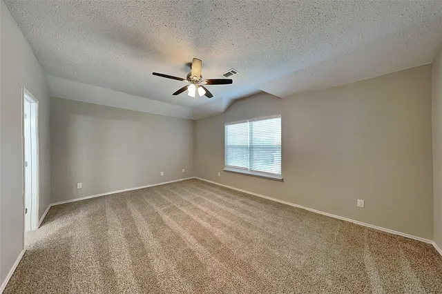 an empty room with windows and ceiling fan