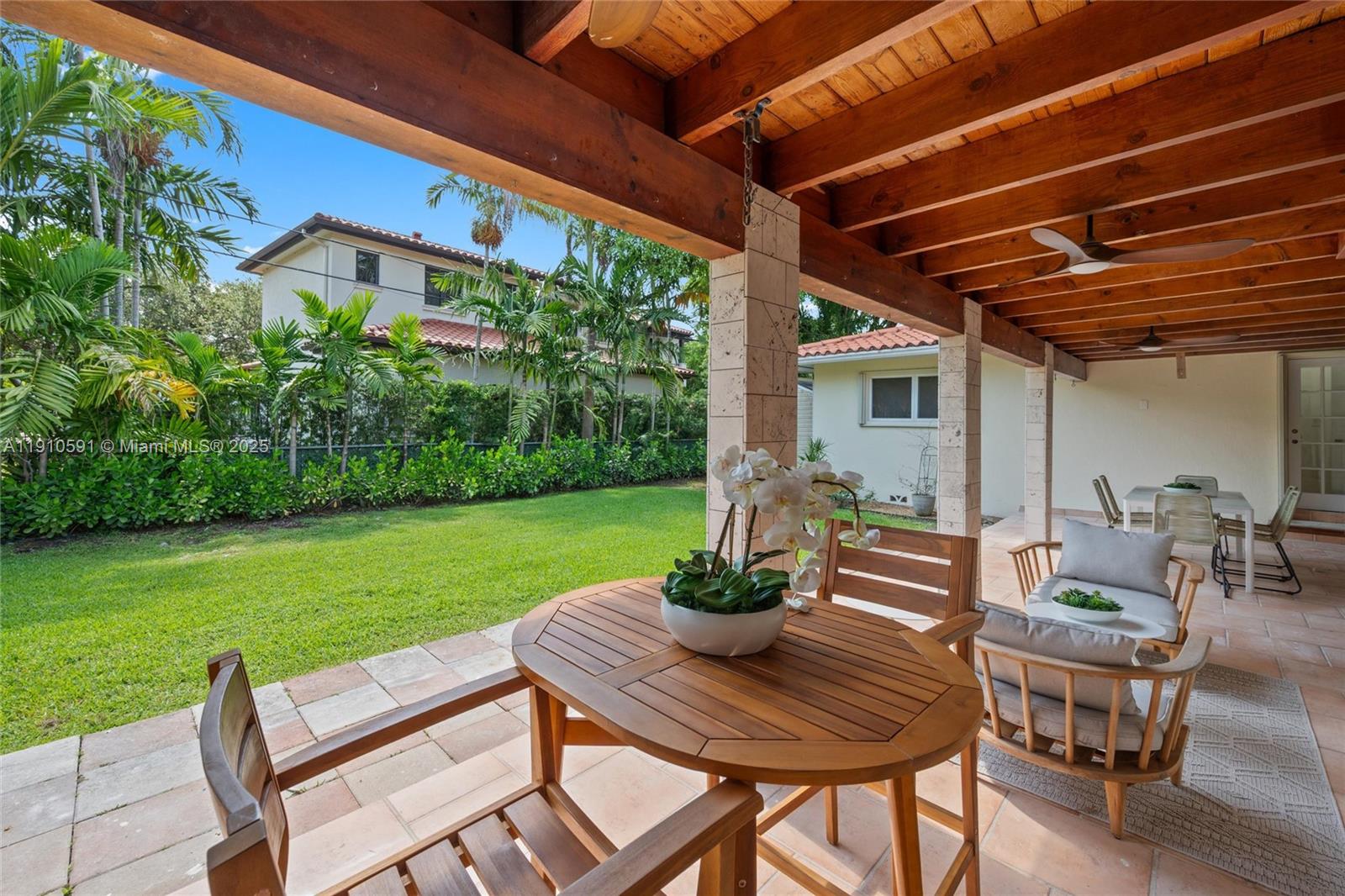 5211 Granada Boulevard Coral Gables, FL 33146 - Photo 25 of 25 a view of a patio with table and chairs and potted plants with wooden floor and fence
