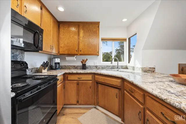 a kitchen with granite countertop stainless steel appliances a sink stove and cabinets