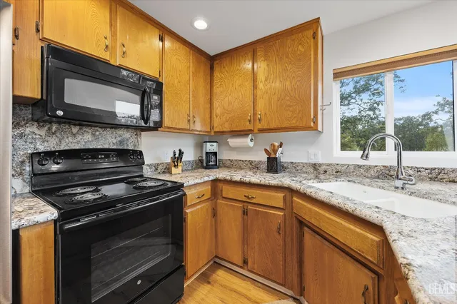 a kitchen with granite countertop a stove sink and microwave
