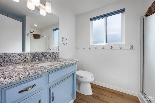 a bathroom with a granite countertop sink a toilet and mirror