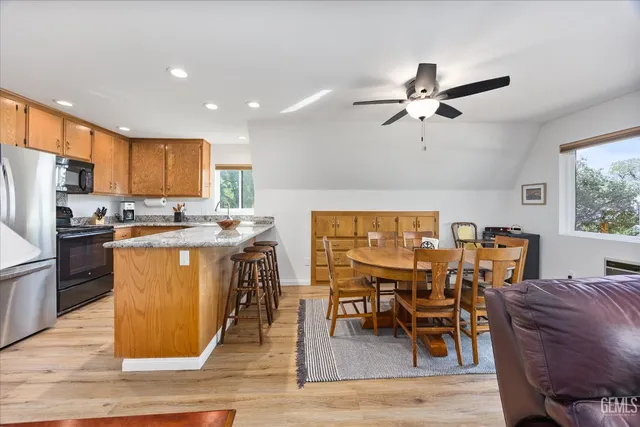 a living room with stainless steel appliances granite countertop furniture wooden floor and a kitchen view
