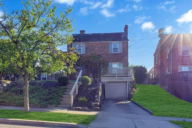 a view of a brick house with a yard and plants