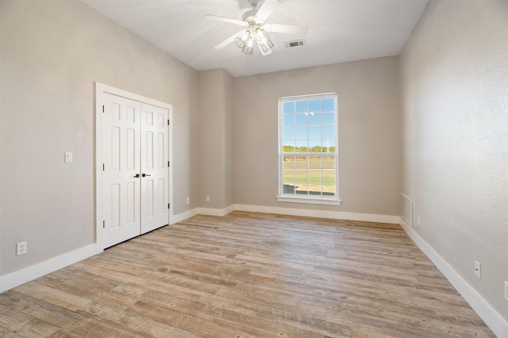 1943 Alsdorf Road Ennis, TX 75119 - Photo 24 of 39 an empty room with wooden floor chandelier fan and windows