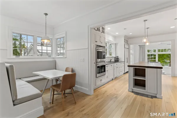 a kitchen with stainless steel appliances granite countertop a stove top oven a sink dishwasher a dining table and chairs with wooden floor