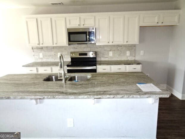 133 Worchester Circle Perry, GA 31069 - Photo 8 of 16 a kitchen with a stove a microwave and white cabinets