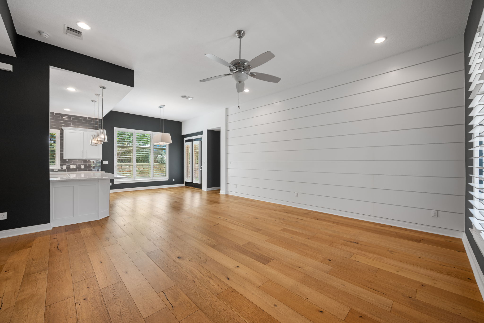 13708 Golden Wave Loop Austin, TX 78738 - Photo 12 of 34 Spacious open concept living area featuring hardwood flooring, a ceiling fan, and a prominent white shiplap accent wall