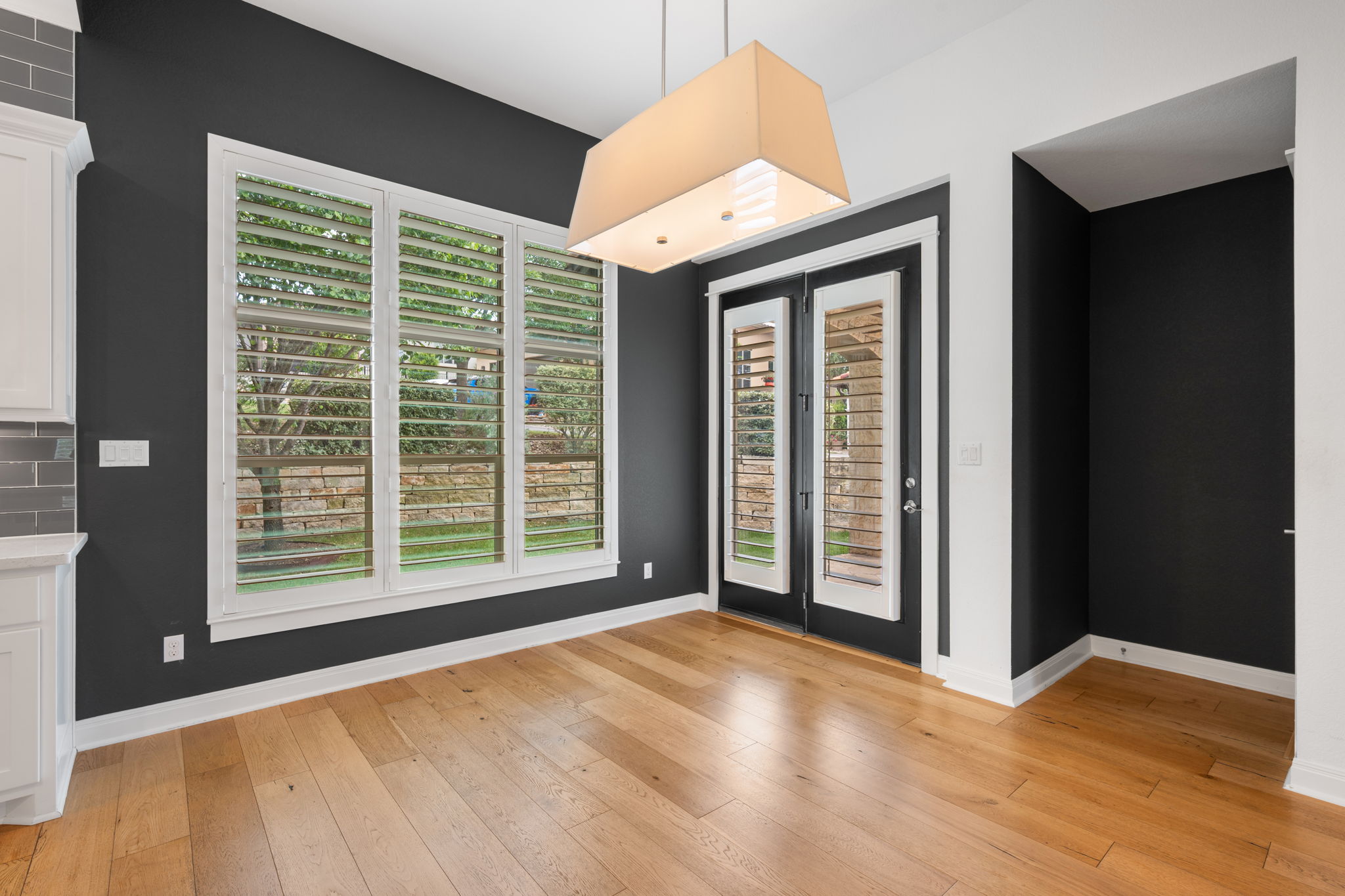 13708 Golden Wave Loop Austin, TX 78738 - Photo 16 of 34 This room features natural wood flooring, a large window with white shutters, and a glass-paneled door