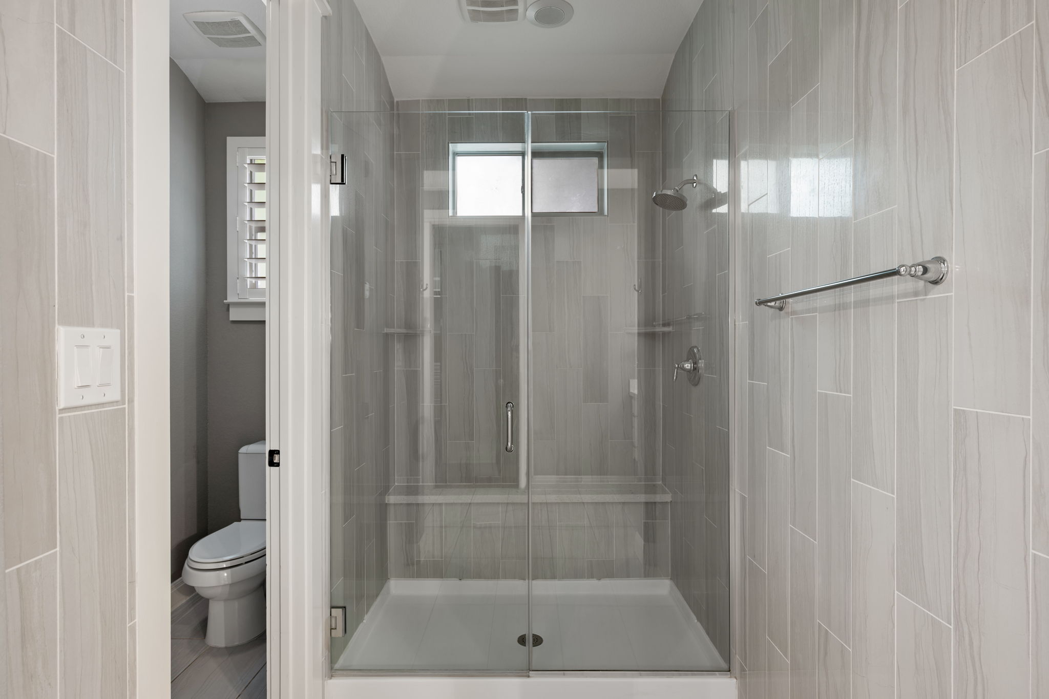 13708 Golden Wave Loop Austin, TX 78738 - Photo 21 of 34 This bathroom features a spacious glass-enclosed shower with light-toned tiled walls, a built-in shower bench, and a modern shower head
