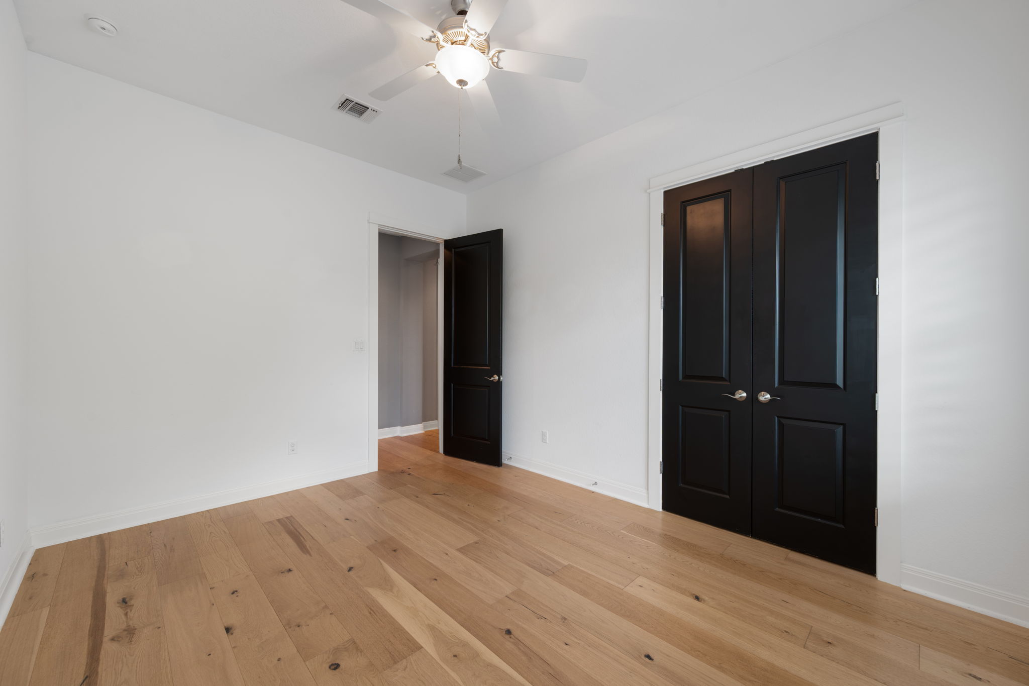 13708 Golden Wave Loop Austin, TX 78738 - Photo 24 of 34 This room features light-toned hardwood flooring, white walls, and a ceiling fan with an integrated light fixture