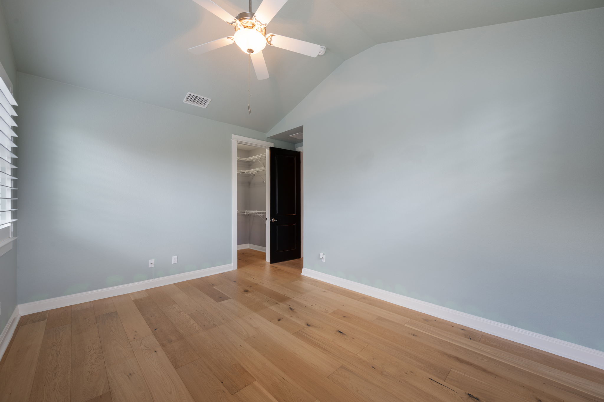 13708 Golden Wave Loop Austin, TX 78738 - Photo 26 of 34 This room features hardwood floors, light blue walls, and a vaulted ceiling with a ceiling fan