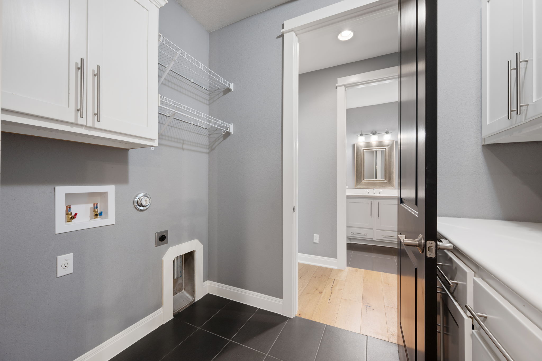 13708 Golden Wave Loop Austin, TX 78738 - Photo 30 of 34 The property features a laundry area with white upper cabinetry, wire shelving, and dark tile flooring