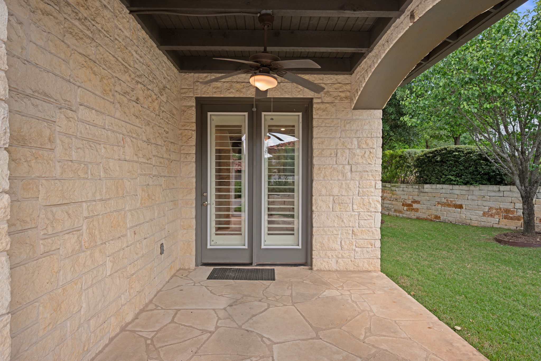 13708 Golden Wave Loop Austin, TX 78738 - Photo 31 of 34 The property features a patio with flagstone paving and a ceiling fan, accessed through double doors with internal blinds