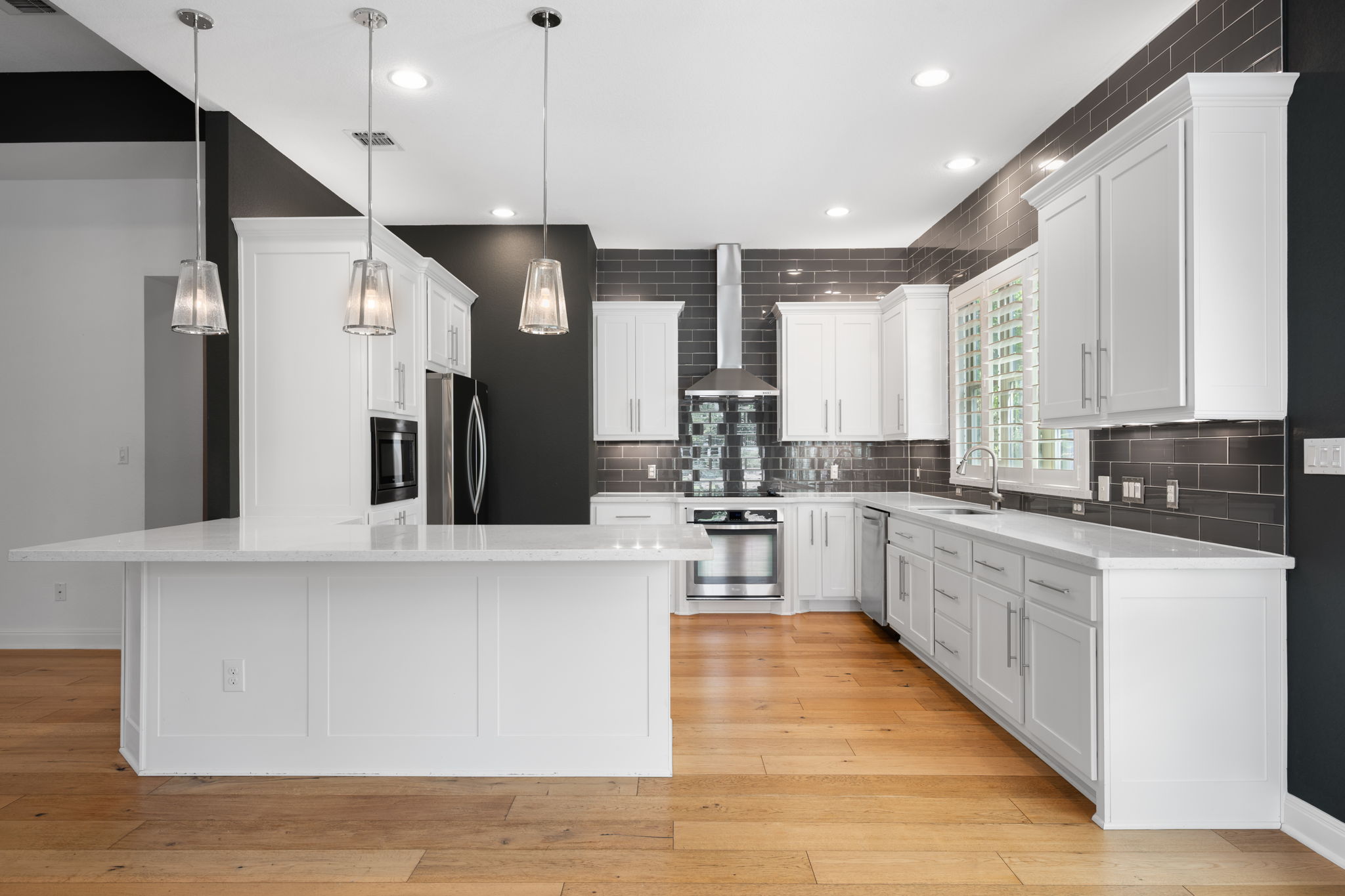 13708 Golden Wave Loop Austin, TX 78738 - Photo 5 of 34 The kitchen features hardwood floors, white cabinetry, and a large island with pendant lighting