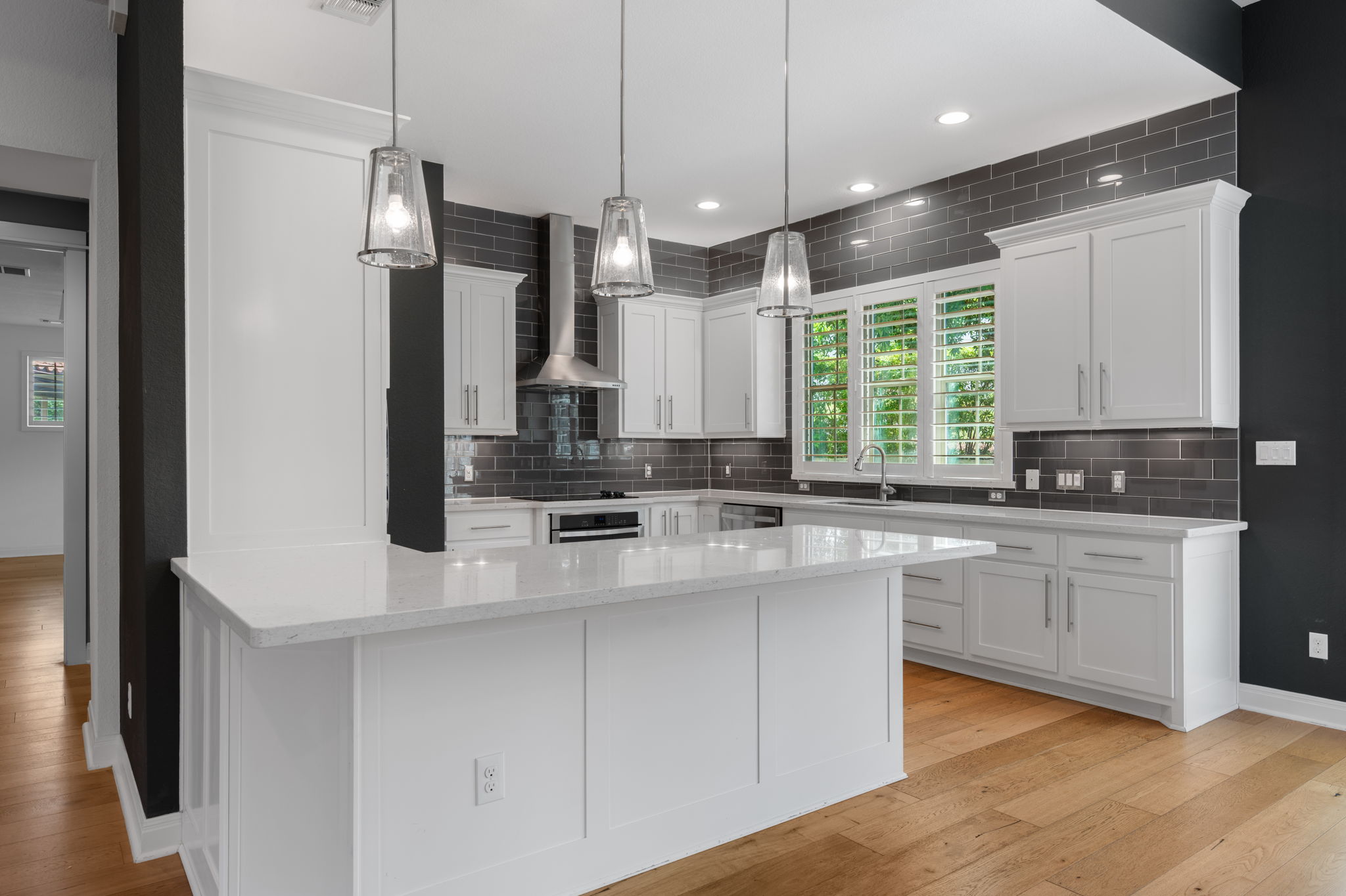 13708 Golden Wave Loop Austin, TX 78738 - Photo 6 of 34 The property features a kitchen with white cabinetry, a large kitchen island with a white countertop, and hardwood flooring
