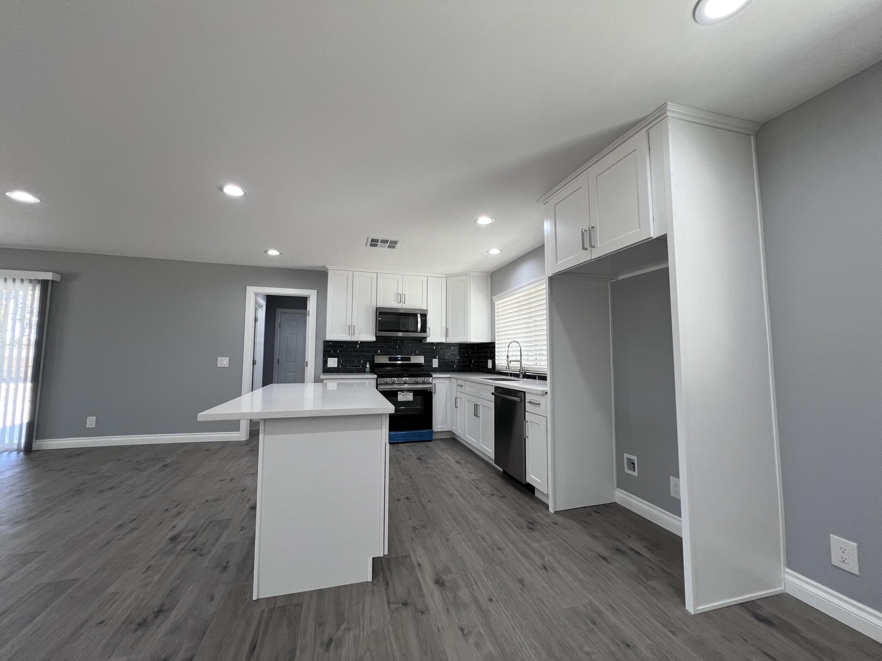 3255 East E Avenue Lancaster, CA 93535 - Photo 26 of 81 a kitchen with a refrigerator a stove top oven and a dining table with wooden floor