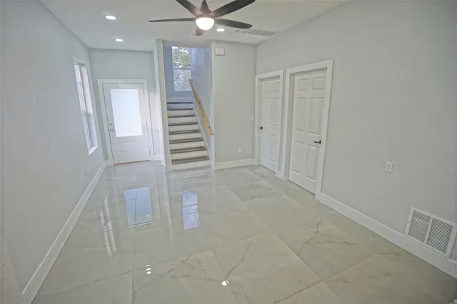 a big room with chandelier fan and windows
