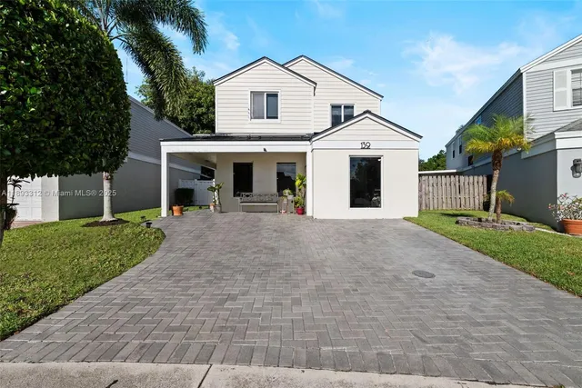 a view of a white house with a yard and large tree