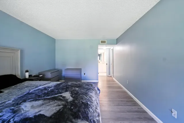 a spacious bedroom with a bed and wooden floor