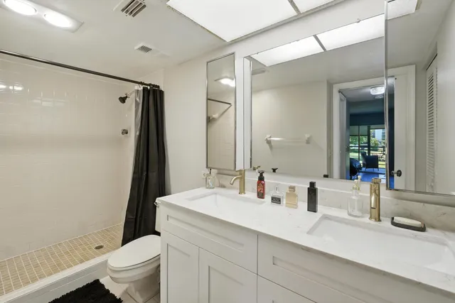 a bathroom with a double vanity sink toilet and shower