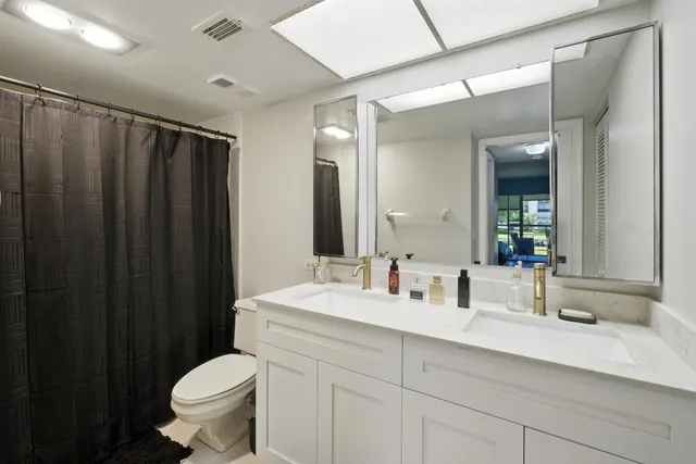 a bathroom with a sink a toilet a mirror and shower curtain