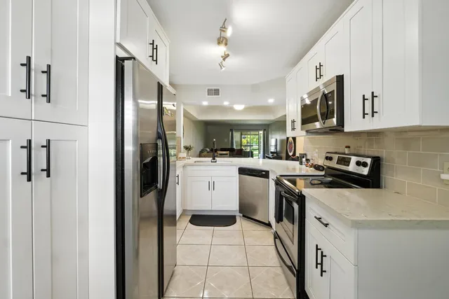 a kitchen with a sink stainless steel appliances and white cabinets