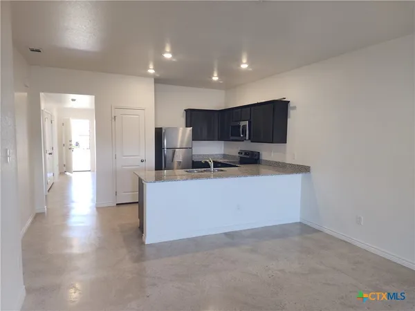 a kitchen with stainless steel appliances granite countertop a stove a sink and a refrigerator