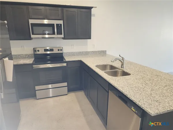 a kitchen with stainless steel appliances granite countertop a sink and a microwave