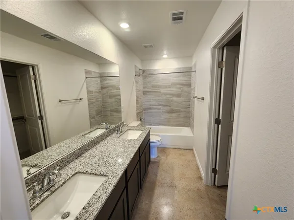 a bathroom with a granite countertop sink a mirror and a bathtub