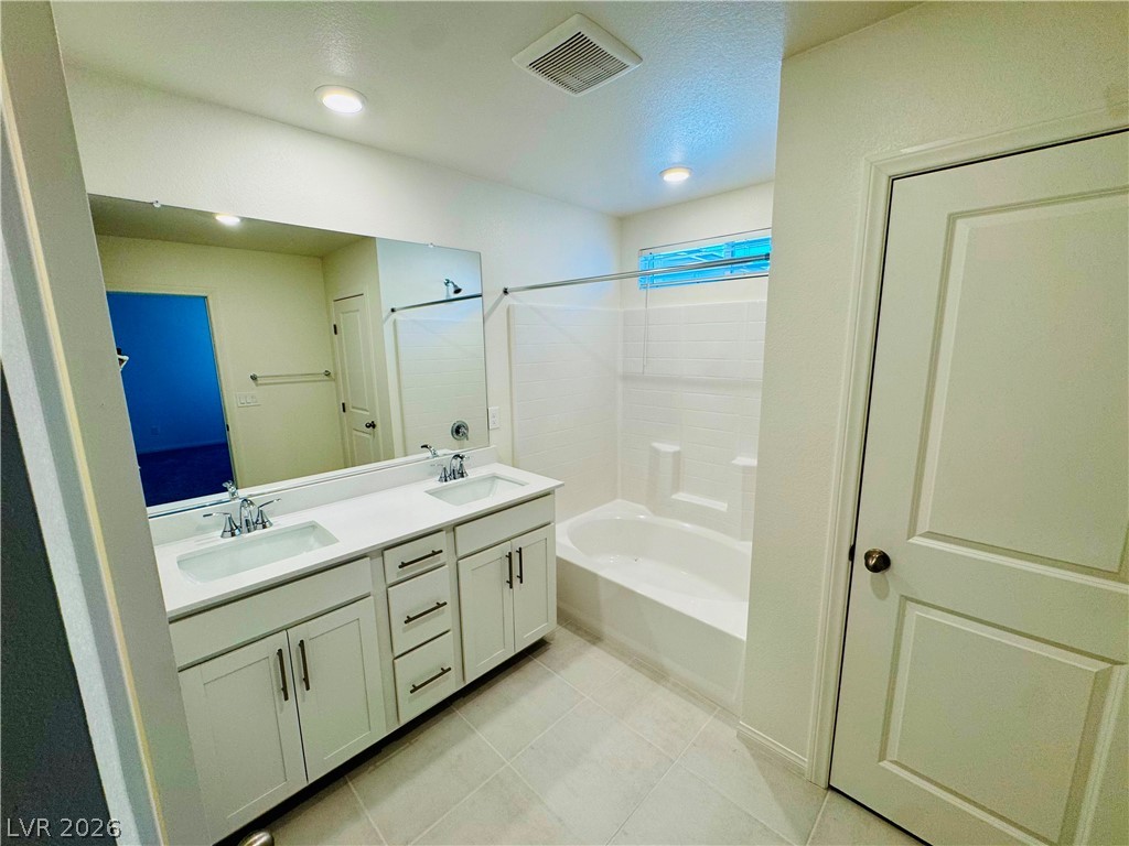9249 Innot Avenue Las Vegas, NV 89148 - Photo 17 of 24 A well-appointed bathroom features a double vanity and a pristine tub with an overhead shower.