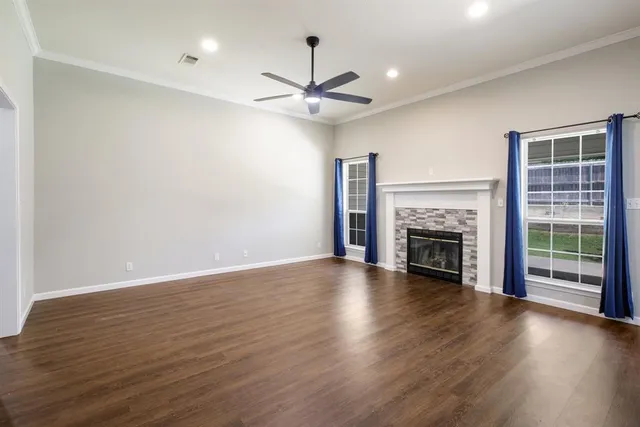 a view of an empty room with wooden floor fireplace and a window