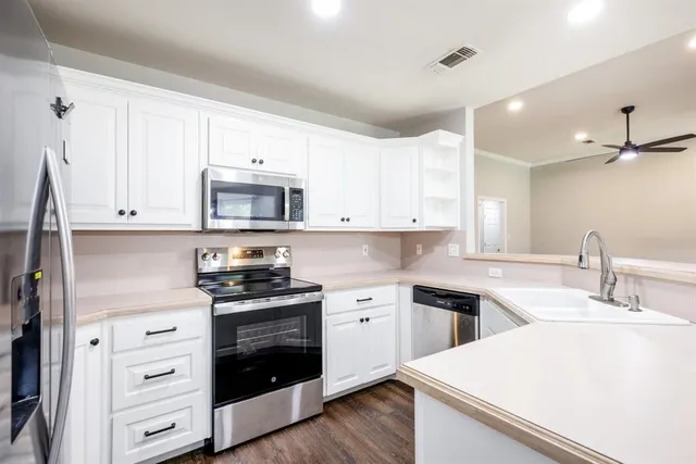 a kitchen with white cabinets and appliances