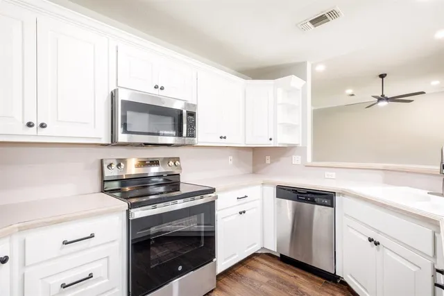 a kitchen with cabinets stainless steel appliances and wooden floor