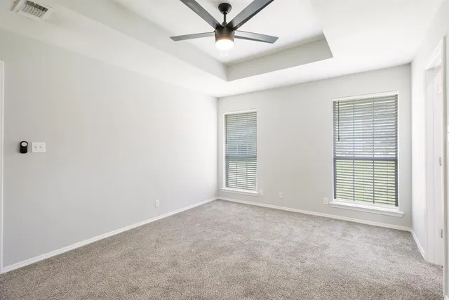 an empty room with windows and fan