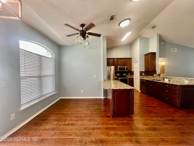 a view of an empty room with wooden floor fireplace and a window