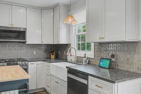 a kitchen with stainless steel appliances granite countertop a sink a stove and a white cabinets