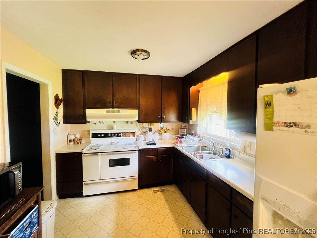10981 Academy Road Laurinburg, NC 28352 - Photo 2 of 8 a kitchen with a sink a stove and refrigerator