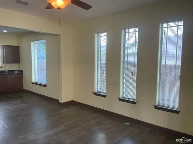 an empty room with wooden floor cabinet and windows