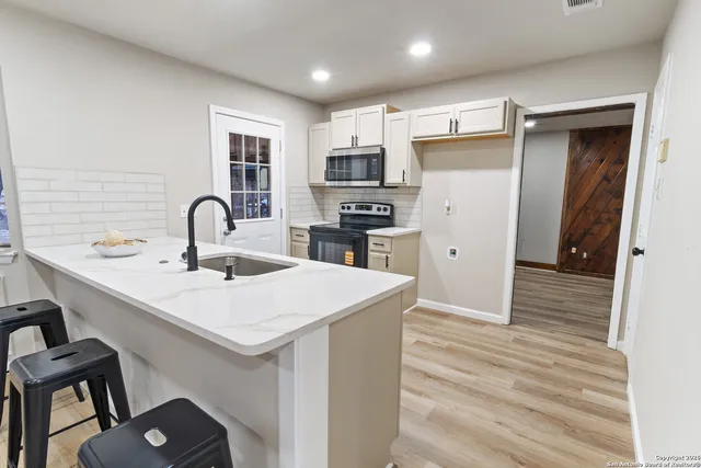 a kitchen with a sink stainless steel appliances a refrigerator and cabinets