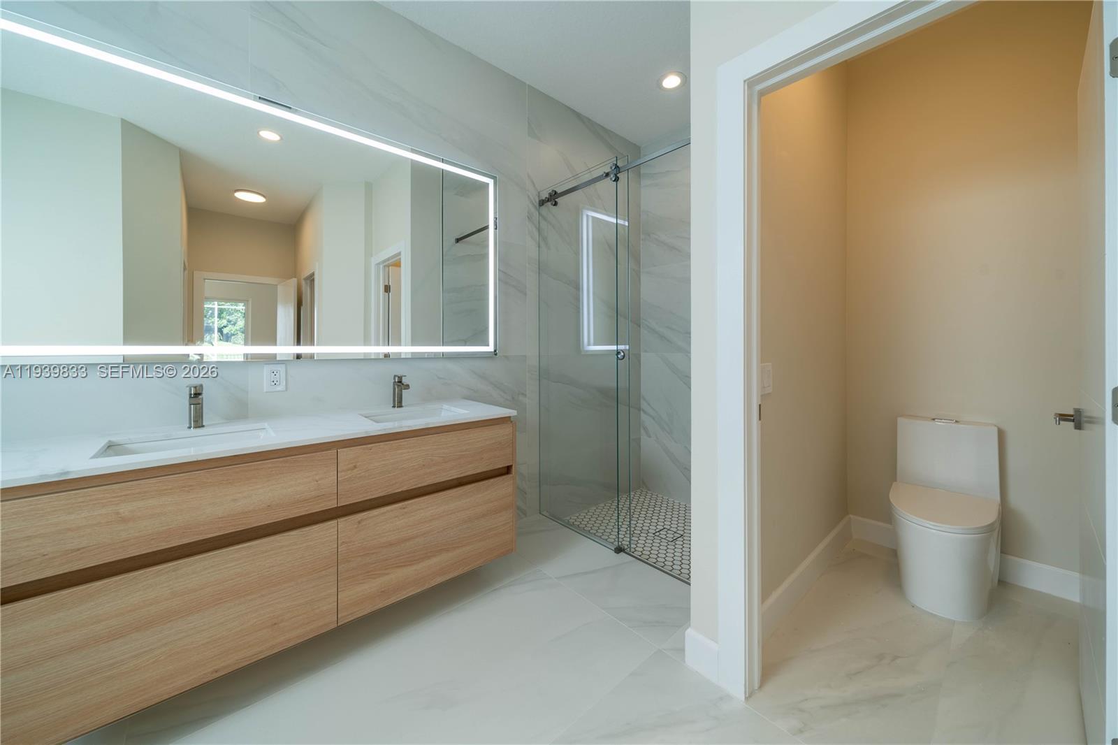 8041 Bermuda Point Lane Davie, FL 33328 - Photo 40 of 60 a bathroom with a double vanity sink toilet and shower
