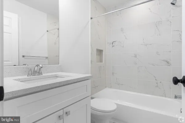 a bathroom with a granite countertop bathtub shower sink vanity and toilet