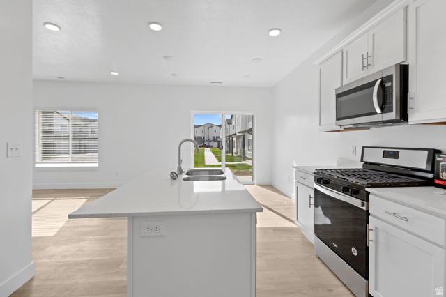 1269 West 500 South Logan, UT 84321 - Photo 6 of 19 Modern kitchen featuring an island with an undermount sink, stainless steel appliances, light-toned cabinetry, and light wood-finish flooring