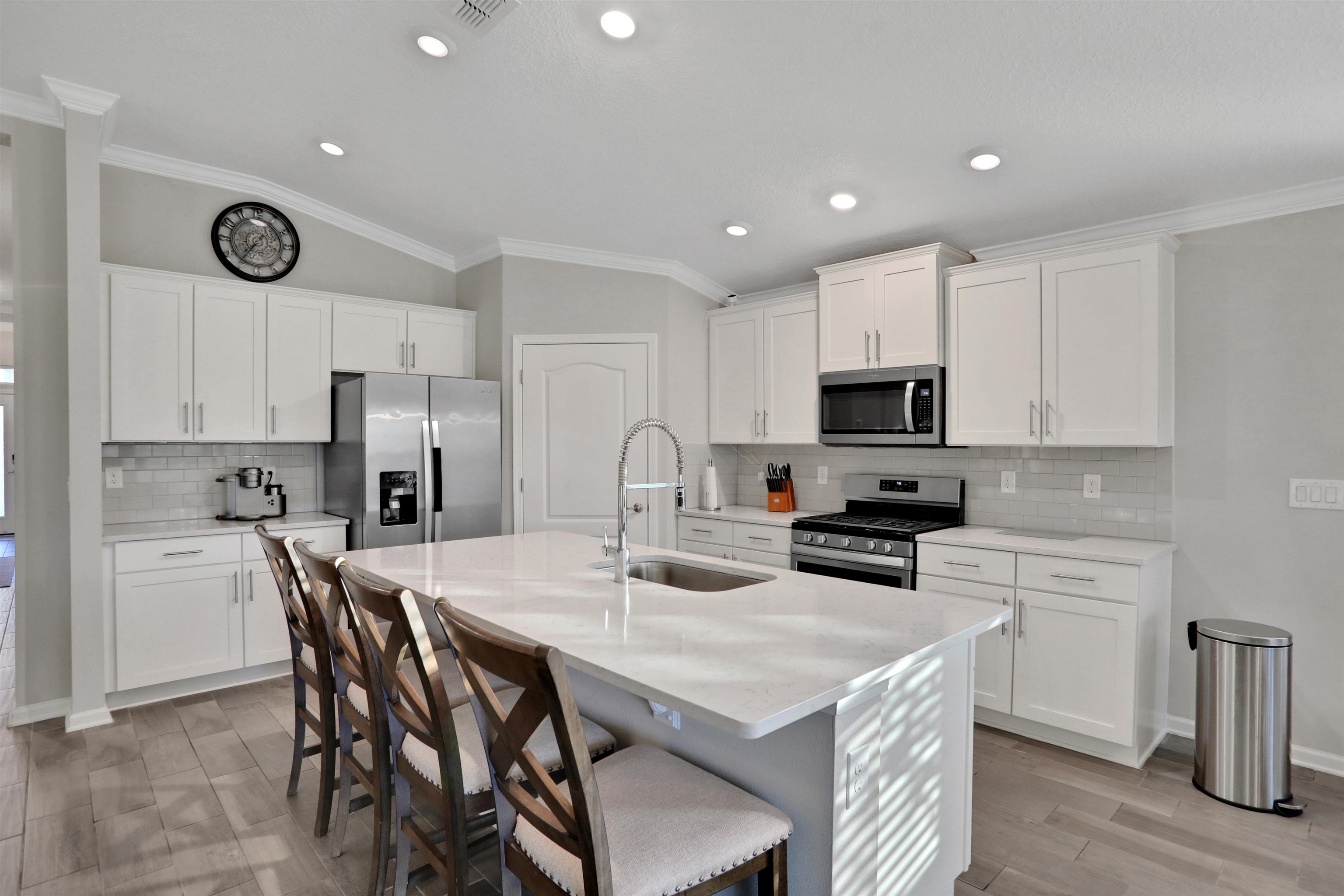 Undisclosed Address St. Augustine, FL 32095 - Photo 18 of 51 Kitchen featuring crown molding, backsplash, a kitchen breakfast bar, stainless steel appliances, and white cabinetry