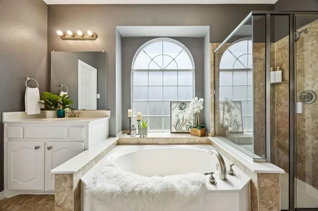 a bathroom with a granite countertop sink a large mirror and a bathtub next to a window
