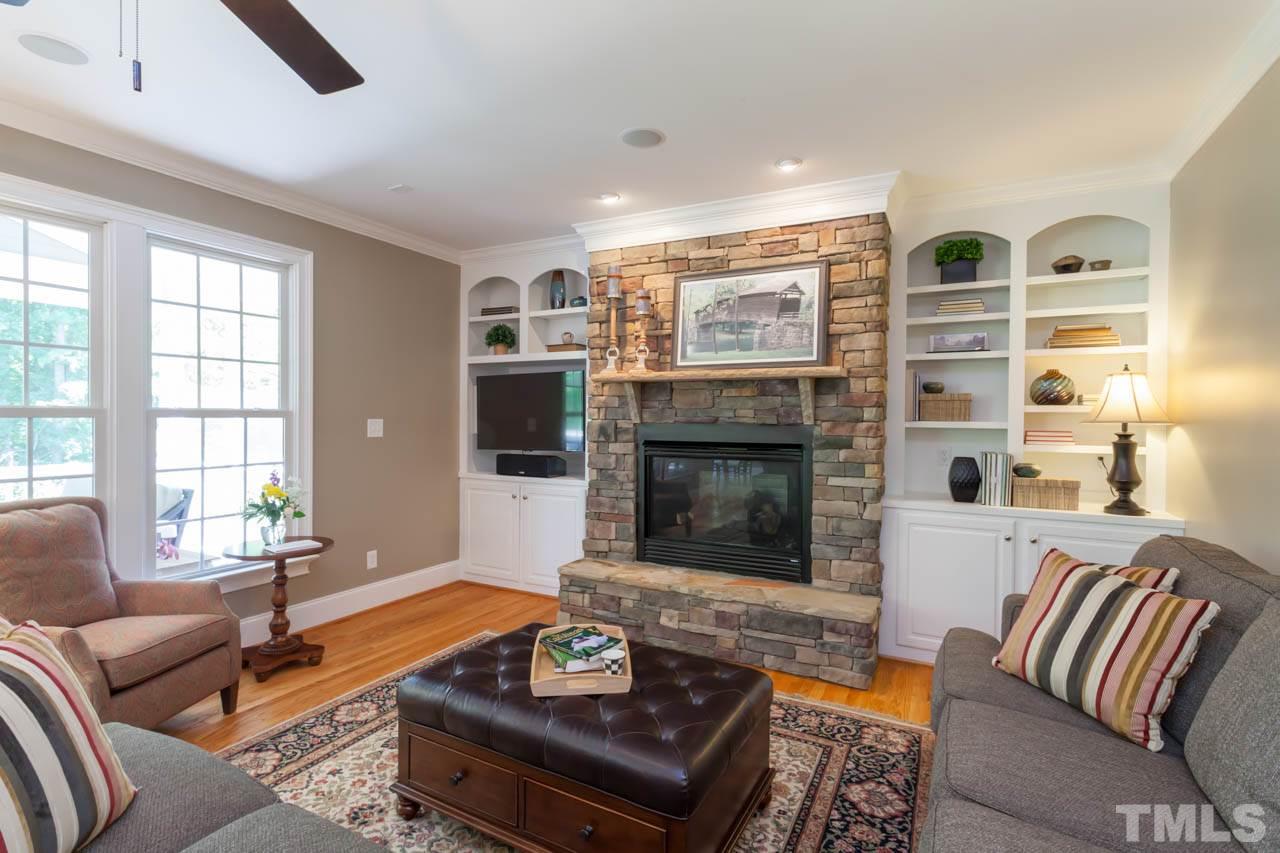 8814 Fidelis Lane Raleigh, NC 27613 - Photo 11 of 25 Beautifully designed Family Room with built-in bookshelves, large wall of windows, crown molding and glowing hardwoods. Beautiful stone surround fireplace.