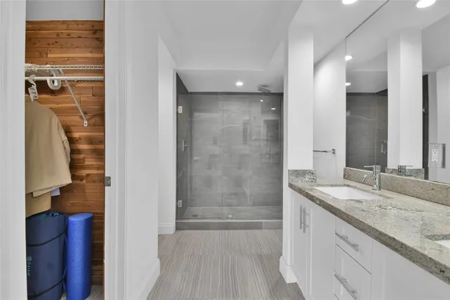 a bathroom with a granite countertop sink a mirror and a shower