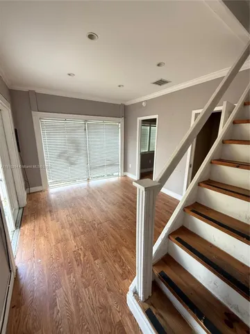 a view of an empty room with wooden floor and stairs